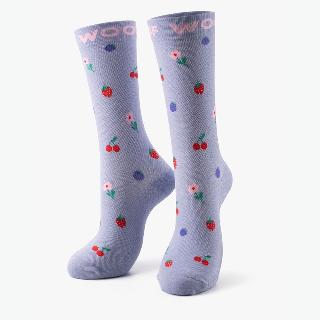 A pair of lavender Cherries & Berries Bamboo Crew Compression Socks standing upright, featuring mini strawberries, cherries, blueberries, and small flowers with pink "WOOF" woven into the top cuffs.