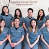 A team of dentists from Sunshine Family Dental wearing cool gray scrub uniforms