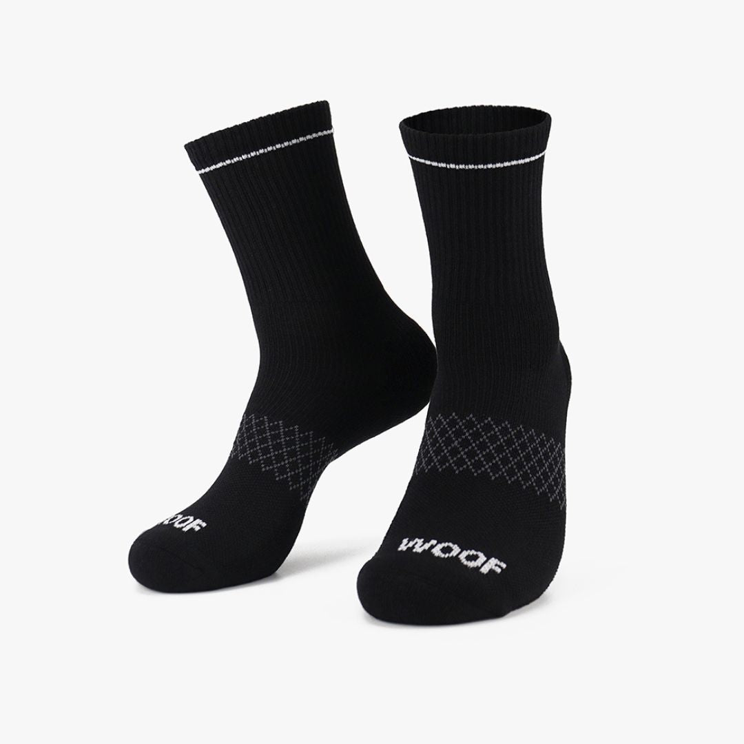 Pair of solid black crew-cut compression socks with white trim detail standing against a plain background.