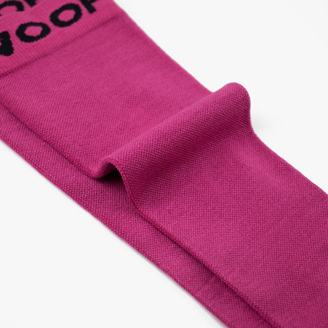 Folded view of solid magenta pink knee-high compression socks showing top cuff branding.